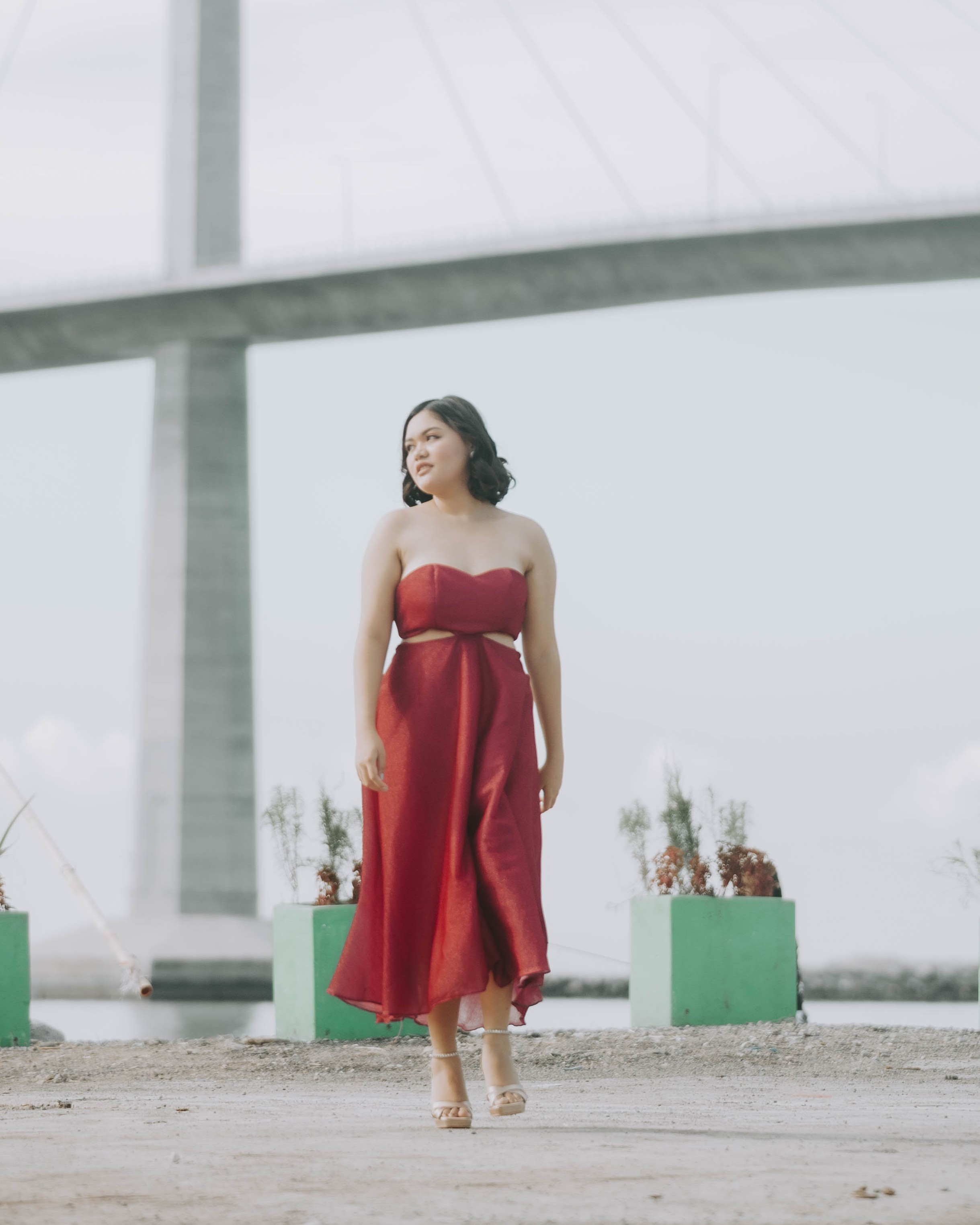 Woman in red dress by the bridge