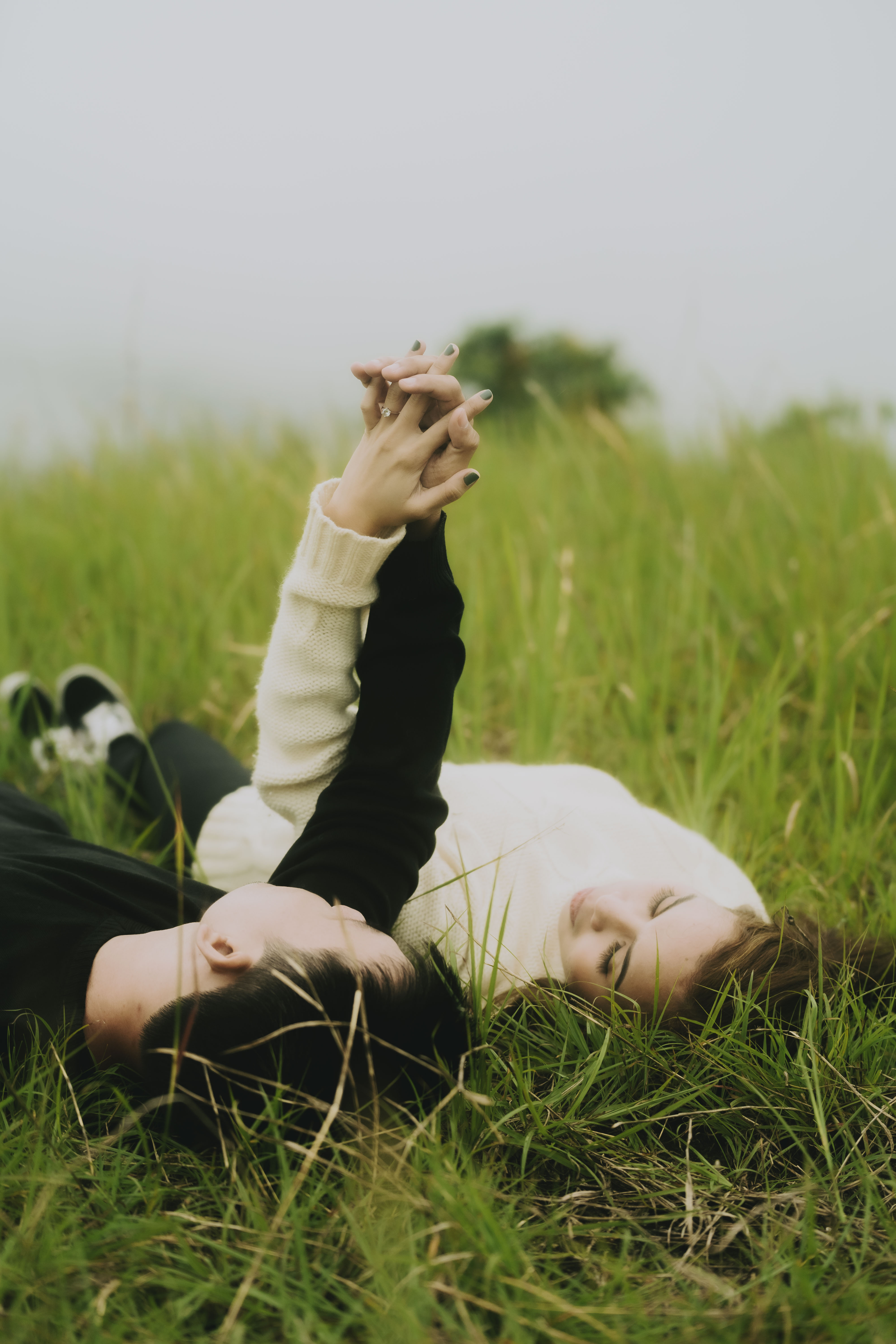 Couple lying in the grass holding hands